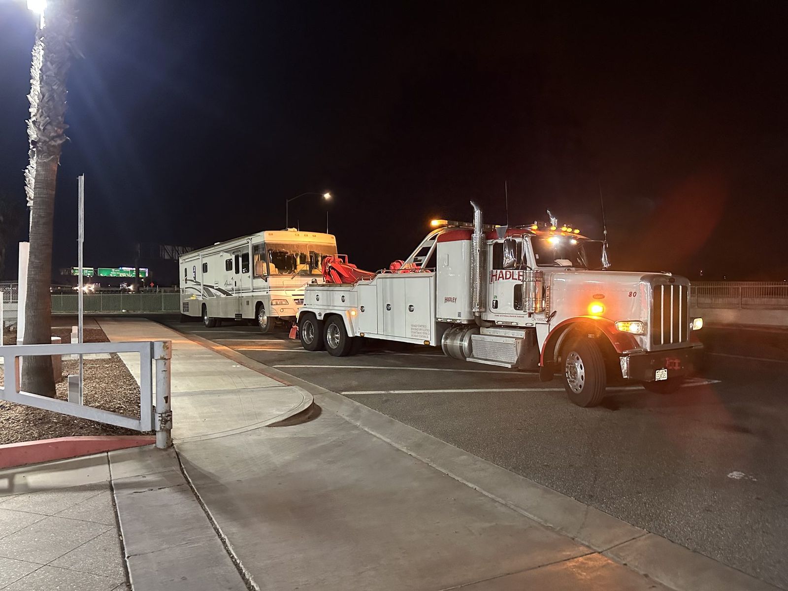 Hadley heavy-duty wrecker recovering a Class A motorhome at night