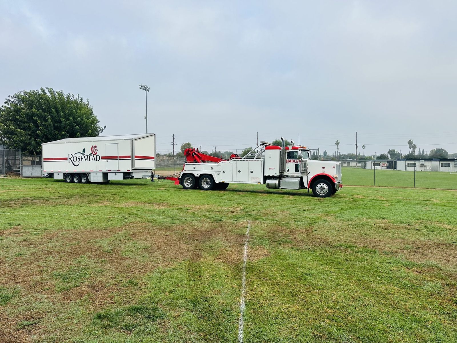 Hadley heavy-duty truck hauling a loaded Rosemead trailer off a field