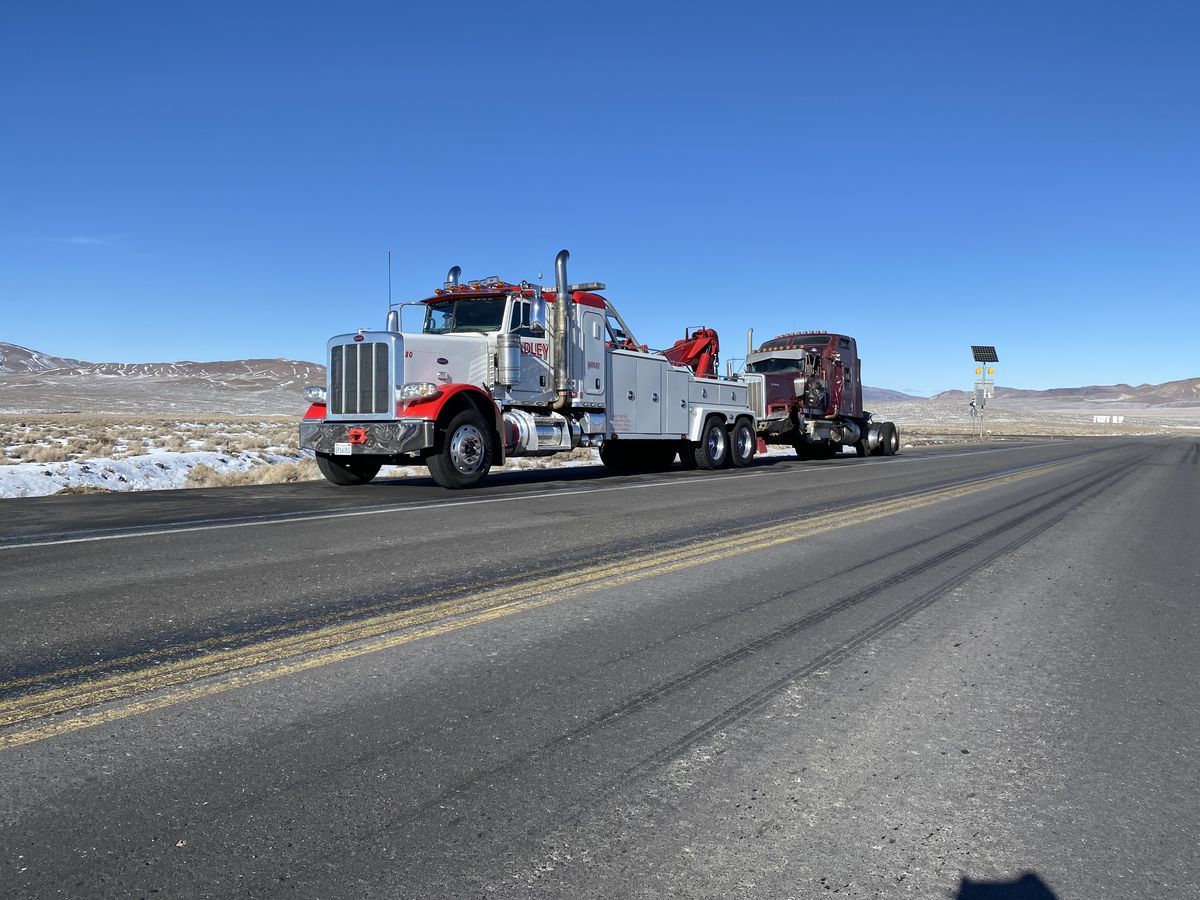 Hadley Peterbilt heavy wrecker towing a sleeper semi across open desert road